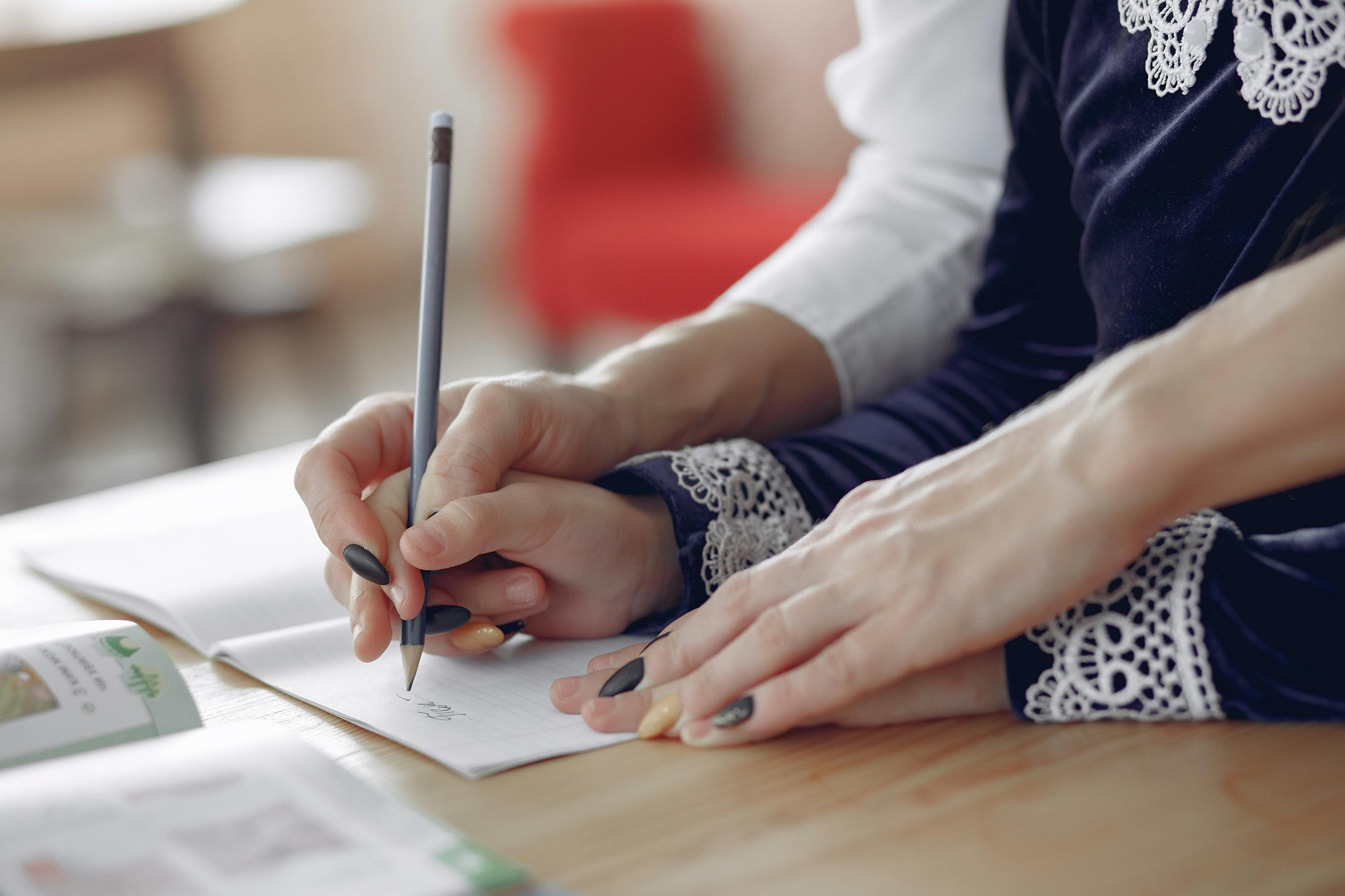 Parent guiding child's handwriting on paper